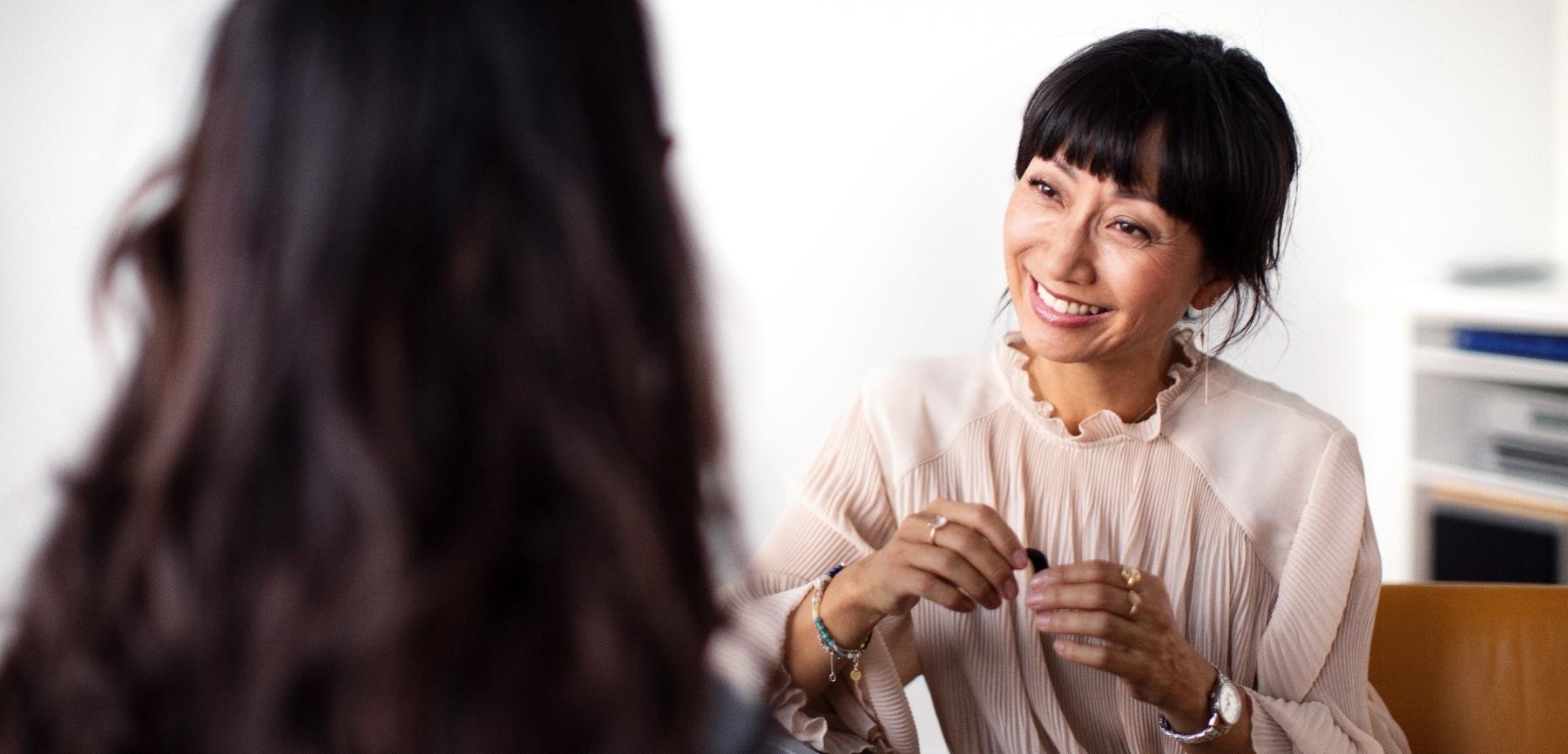 A Piccolo Hearing audiologist fitting a hearing aid for a smiling patient